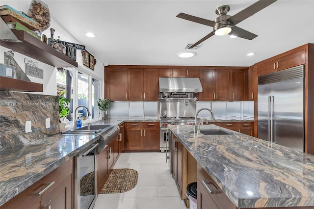 kitchen with dark stone countertops, wine cooler, built in refrigerator, sink, and tasteful backsplash