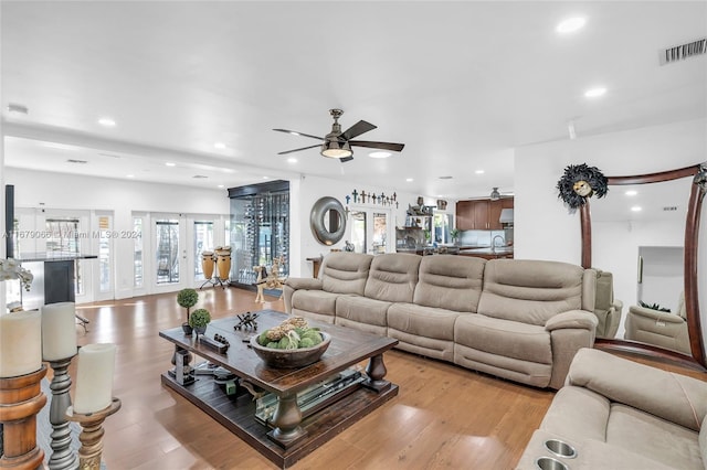 living room featuring sink, light hardwood / wood-style floors, and ceiling fan