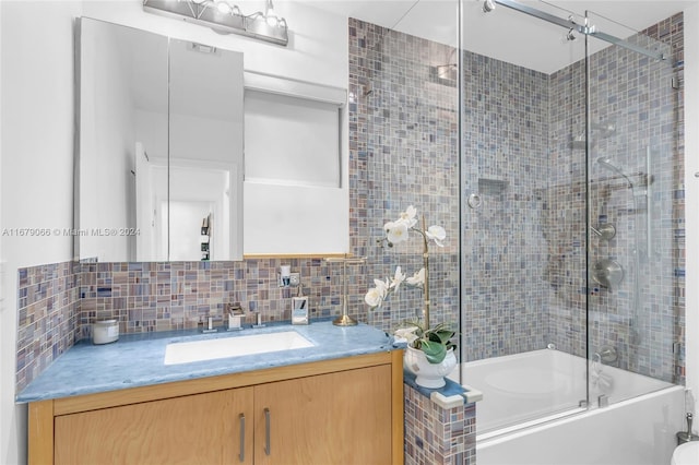 bathroom featuring vanity, combined bath / shower with glass door, and decorative backsplash