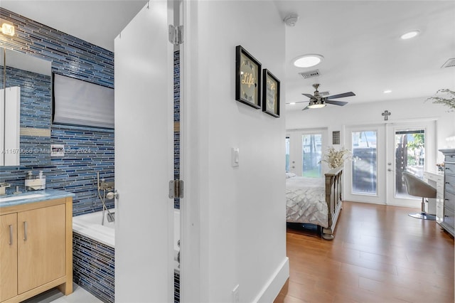 bathroom featuring a tub, tasteful backsplash, ceiling fan, hardwood / wood-style flooring, and vanity