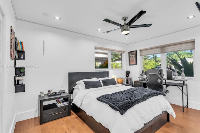 bedroom with ceiling fan, hardwood / wood-style flooring, and multiple windows