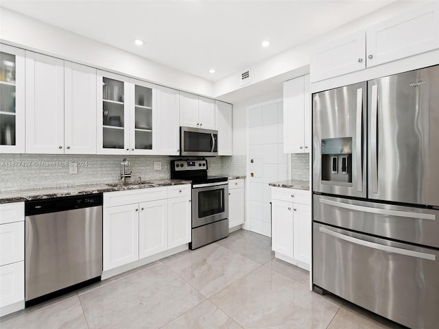 kitchen featuring decorative backsplash, appliances with stainless steel finishes, white cabinetry, sink, and light stone counters