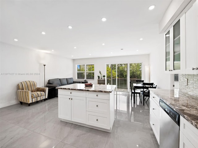 kitchen featuring white cabinets, a kitchen island, backsplash, light stone countertops, and dishwasher