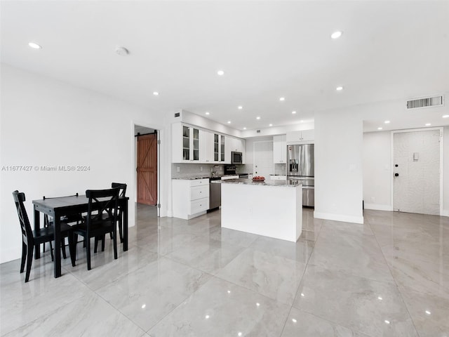 kitchen featuring appliances with stainless steel finishes, a barn door, a kitchen island, and white cabinets