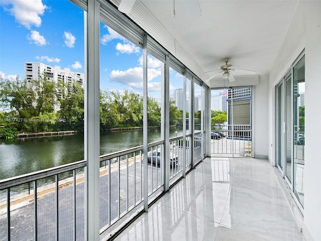 unfurnished sunroom featuring a water view and ceiling fan