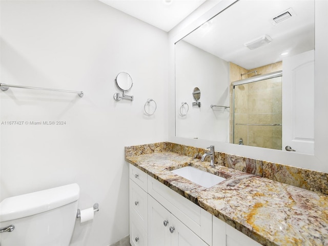 bathroom featuring toilet, an enclosed shower, and vanity