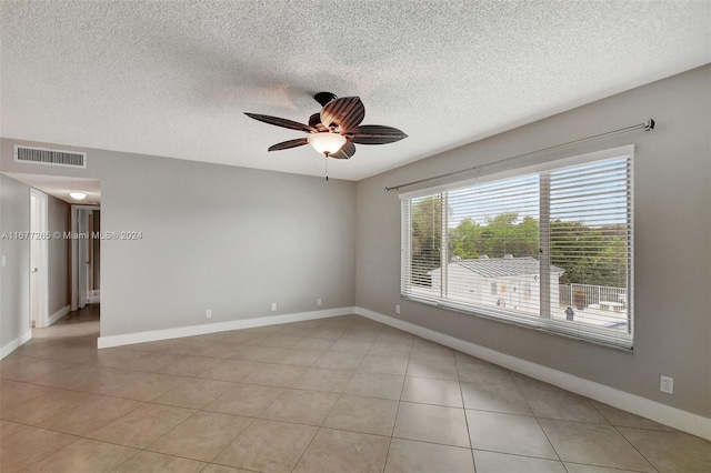 empty room featuring a textured ceiling, light tile patterned floors, and ceiling fan