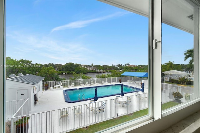 view of pool with a patio, an outdoor structure, and a water view