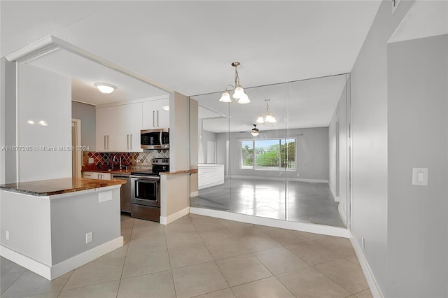 kitchen featuring white cabinets, a notable chandelier, pendant lighting, appliances with stainless steel finishes, and tasteful backsplash