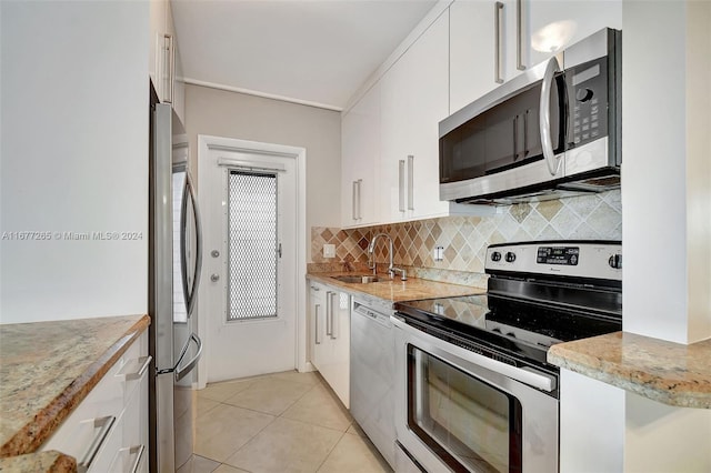 kitchen with sink, appliances with stainless steel finishes, white cabinetry, and light tile patterned floors