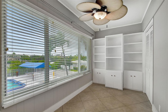 interior space with ornamental molding, ceiling fan, and light tile patterned floors