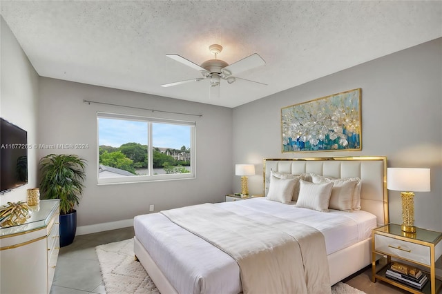 tiled bedroom with ceiling fan and a textured ceiling