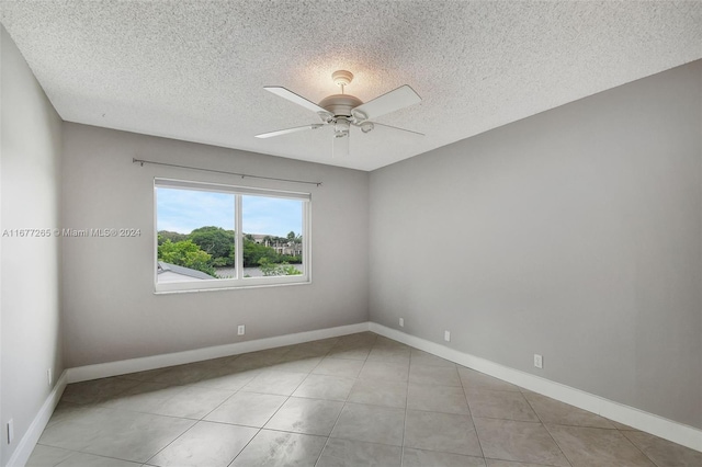 empty room with a textured ceiling, light tile patterned floors, and ceiling fan