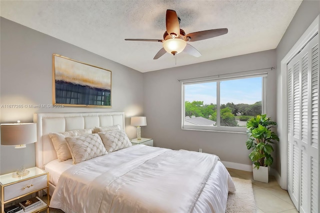 bedroom featuring light tile patterned flooring, a textured ceiling, a closet, and ceiling fan