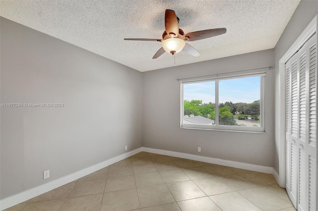 tiled empty room featuring a textured ceiling and ceiling fan