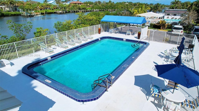 view of swimming pool featuring a patio and a water view