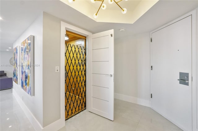 hall with a notable chandelier and light tile patterned floors