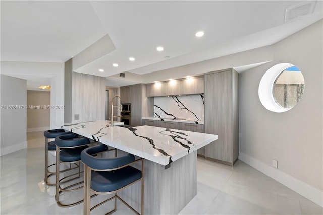 kitchen with light stone countertops, a kitchen bar, stainless steel microwave, and kitchen peninsula