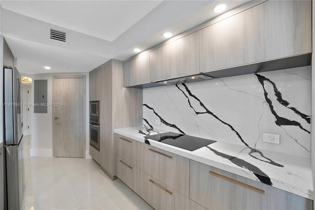 kitchen featuring light brown cabinets, light tile patterned floors, stainless steel refrigerator, black electric stovetop, and light stone counters