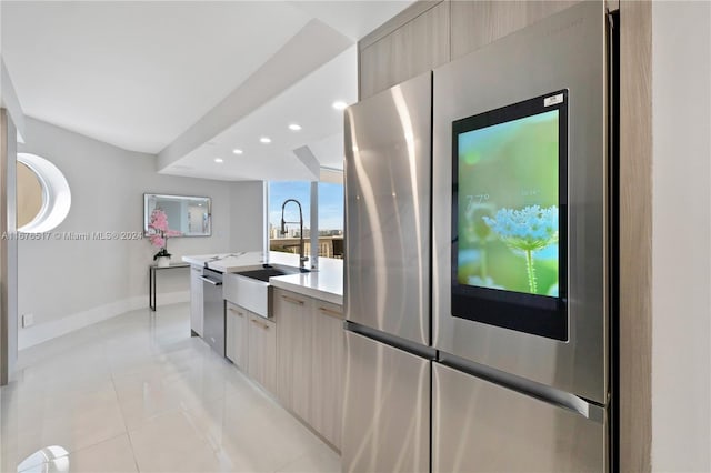 kitchen featuring light brown cabinetry, light tile patterned flooring, appliances with stainless steel finishes, and sink