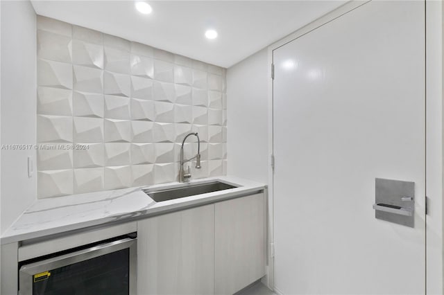 interior space with light stone counters, sink, backsplash, and beverage cooler