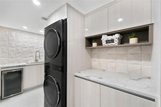 laundry area featuring stacked washer / dryer, beverage cooler, and sink