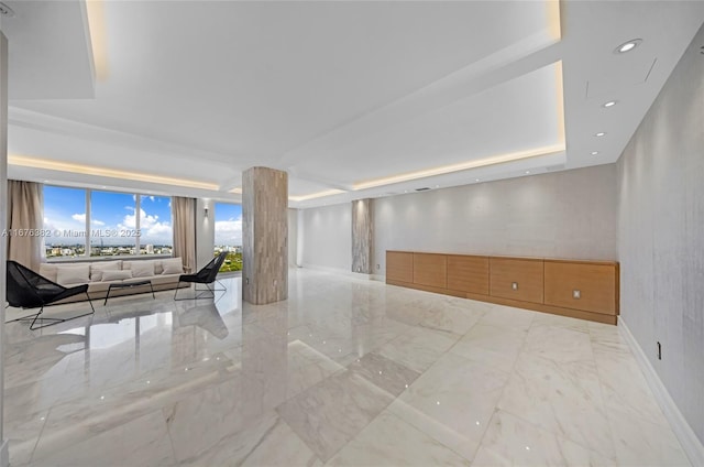 unfurnished living room with baseboards, marble finish floor, a tray ceiling, and recessed lighting