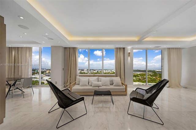 living room with a raised ceiling and floor to ceiling windows