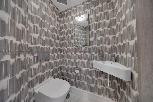 bathroom featuring sink, toilet, and tile walls