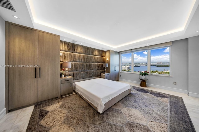 bedroom with a water view and a raised ceiling