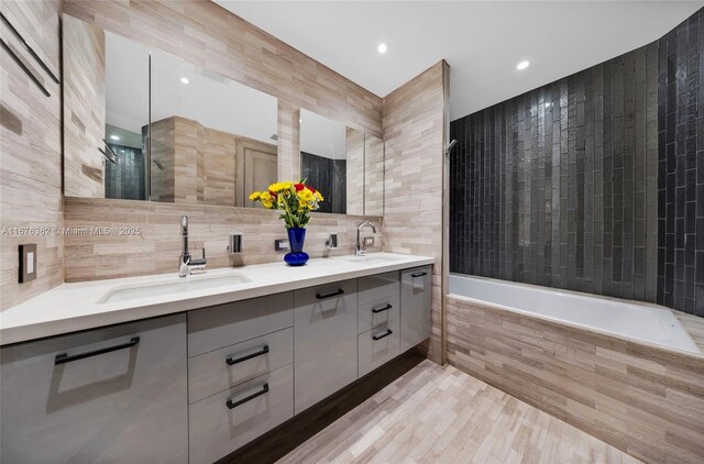 bathroom featuring hardwood / wood-style floors, vanity, independent shower and bath, and tile walls