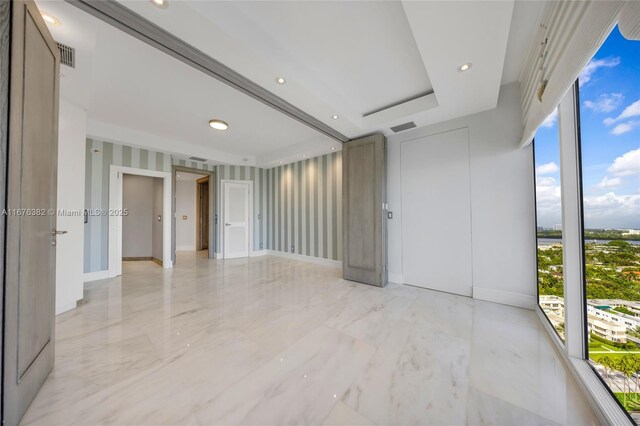 unfurnished room featuring plenty of natural light and a raised ceiling