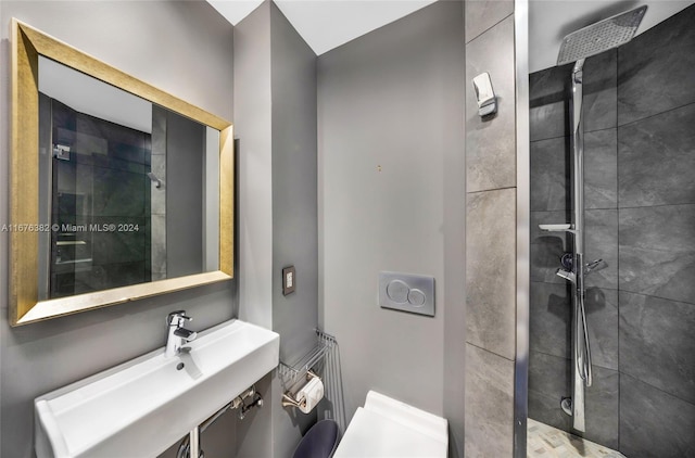 bathroom with tiled shower, toilet, and sink