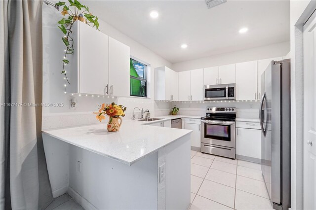 kitchen featuring white cabinetry, light tile patterned floors, light stone counters, kitchen peninsula, and stainless steel appliances