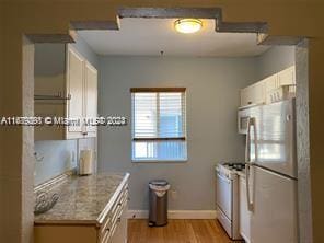 kitchen with white cabinets, light hardwood / wood-style floors, and white appliances