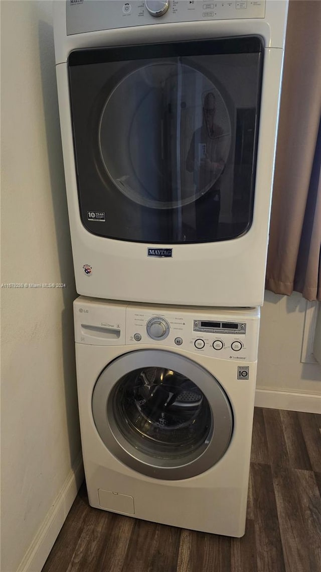 clothes washing area with dark hardwood / wood-style flooring and stacked washing maching and dryer