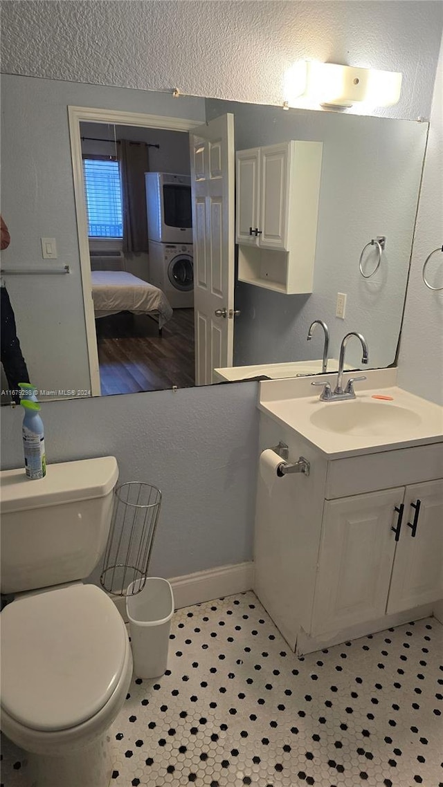 bathroom with wood-type flooring, vanity, toilet, and stacked washer / drying machine