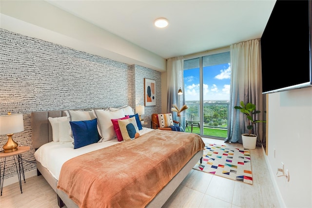 bedroom featuring light hardwood / wood-style floors, access to exterior, and floor to ceiling windows