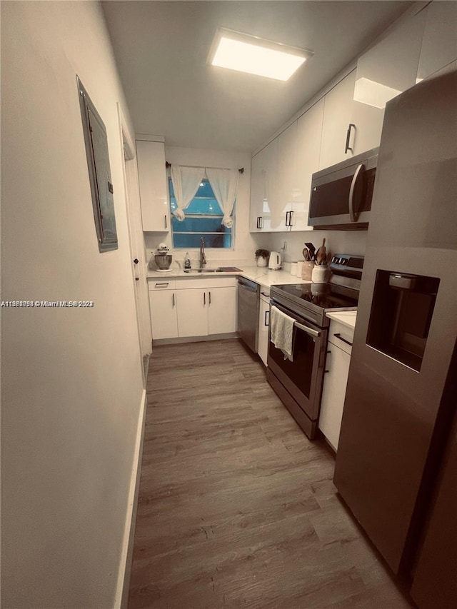 kitchen featuring appliances with stainless steel finishes, white cabinets, sink, and light wood-type flooring