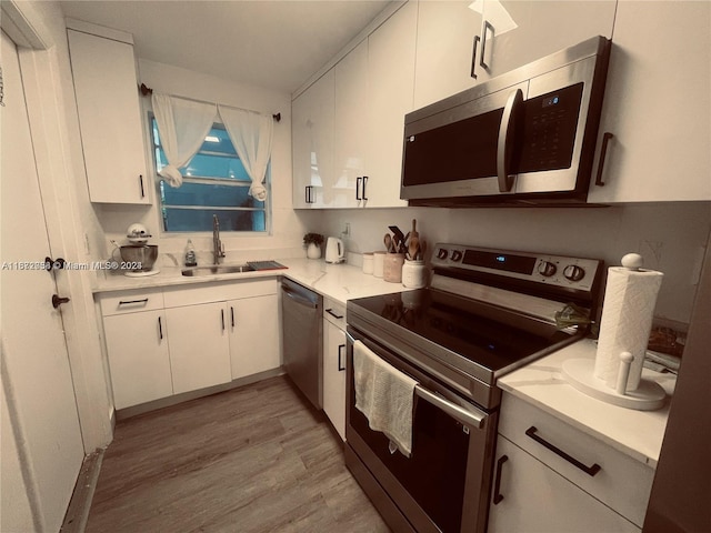 kitchen with light hardwood / wood-style floors, stainless steel appliances, sink, and white cabinets