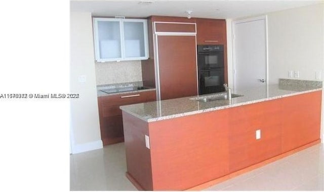 1830 S Ocean Dr Unit 3307, Hallandale Beach, FL 33009 - kitchen with black appliances, a peninsula, light stone countertops, decorative backsplash, and brown cabinets