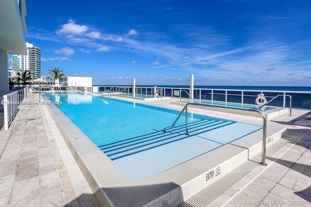 view of pool featuring a patio area and a water view