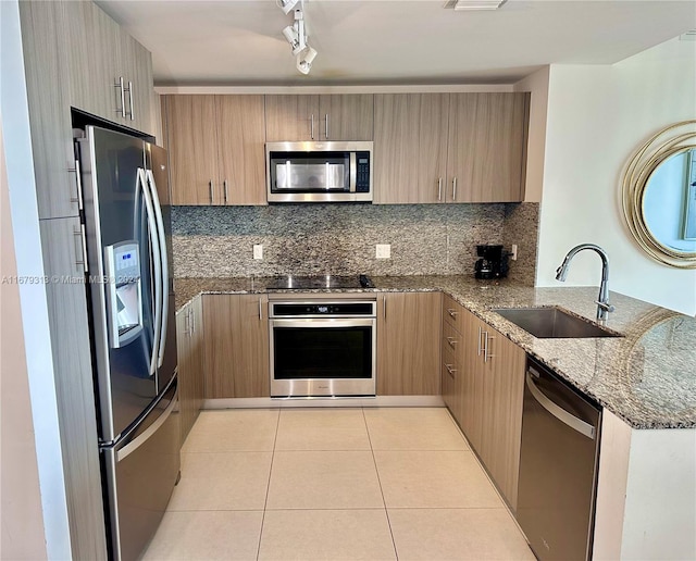 kitchen with stone countertops, appliances with stainless steel finishes, sink, and kitchen peninsula