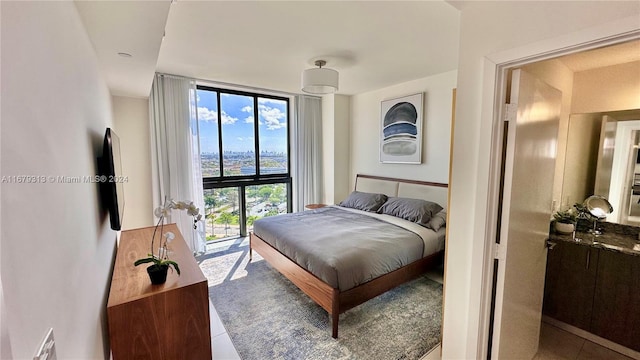 bedroom featuring a wall of windows, access to outside, and tile patterned flooring