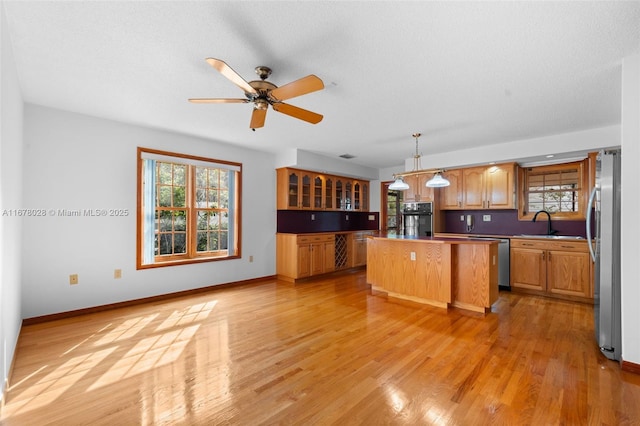 kitchen featuring sink, a center island, light hardwood / wood-style flooring, appliances with stainless steel finishes, and pendant lighting