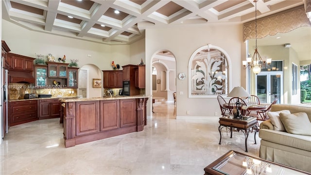 kitchen with coffered ceiling, a high ceiling, decorative light fixtures, and a chandelier