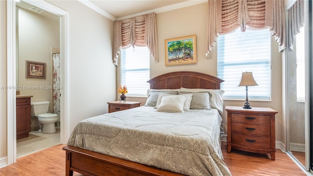 bedroom with multiple windows, hardwood / wood-style floors, ensuite bath, and crown molding