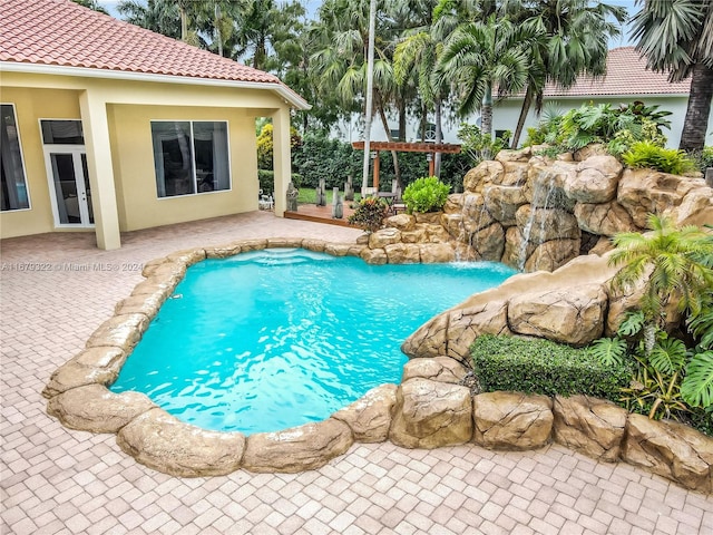 view of pool with a patio, french doors, pool water feature, and a pergola