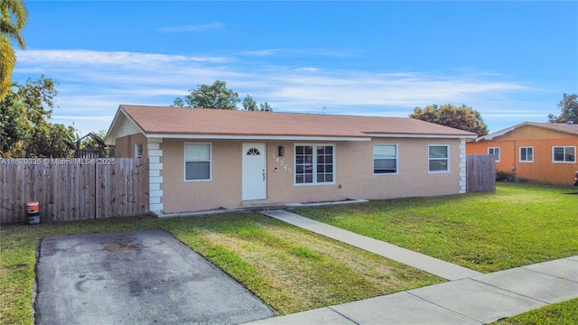 ranch-style house with a front yard, fence, and stucco siding