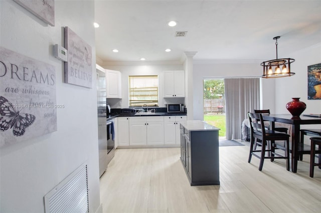 kitchen featuring a center island, sink, crown molding, decorative light fixtures, and white cabinets